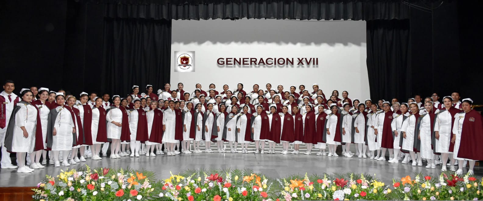 Generación XVII de egresados reunida en el escenario durante la ceremonia de graduación.